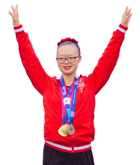Women in red jacket with medals around her neck and arms in the air.